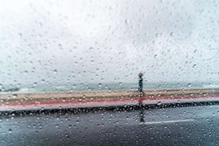Salvador, Bahia, Brazil - November 15, 2021: A person walking along the waterfront in the middle of the rain. Salvador, Bahia, Brazil.の写真素材