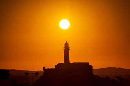 Salvador, Bahia, Brazil - September 19, 2021: Silhouette of a lighthouse against a beautiful and dramatic orange sunset on Barra beach in Salvador, city in the Brazilian state of Bahia.のeditorial素材