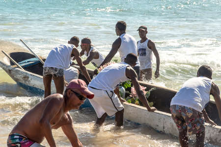 Salvador, Bahia, Brazil - January 20, 2019: Fishermen putting canoe into the sea for delivery of IemanjÃ¡'s gifts at Boca do Rio beach in Salvador, Bahia, Brazil.のeditorial素材