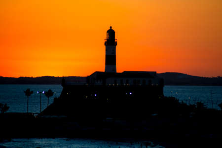 Salvador, Bahia, Brazil - September 19, 2021: Silhouette of a lighthouse against a beautiful and dramatic orange sunset on Barra beach in Salvador, city in the Brazilian state of Bahia.のeditorial素材