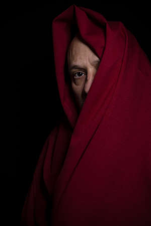 Man covered with red cloth against a black background. Salvador, Bahia, Brazil.
