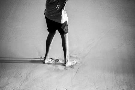 Salvador, Bahia, Brazil - September 26, 2021: Lower part of a person standing on the beach sand....