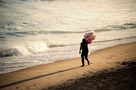 Salvador, Bahia, Brazil - September 26, 2021: Cotton candy seller walking on the sand of Farol da Barra beach in Salvador city, Bahia state, Brazil.のeditorial素材
