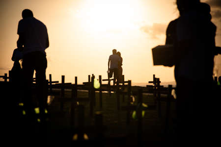 Salvador, Bahia, Brazil - October 01, 2021: Silhouette of people and crosses fixed on the ground in honor of those killed by covid-19. Sunset in Salvador, Bahia, Brazil.のeditorial素材