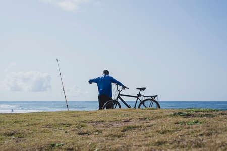 Salvador, Bahia, Brazil - October 10, 2021: Fisherman and his bike getting ready for fishing at Boca do Rio beach In Salvador, Bahia, Brazil.のeditorial素材