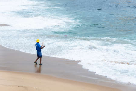 A man fishing for fish on the beach of the Rio Vermelho. City of Salvador, Bahia, Brazil.のeditorial素材