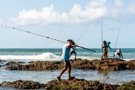 Salvador, Bahia, Brazil - October 10, 2021: Fishermen with fishing rod on the rocks fishing on the famous Boca do Rio beach in Salvador, capital of Bahia, Brazilのeditorial素材