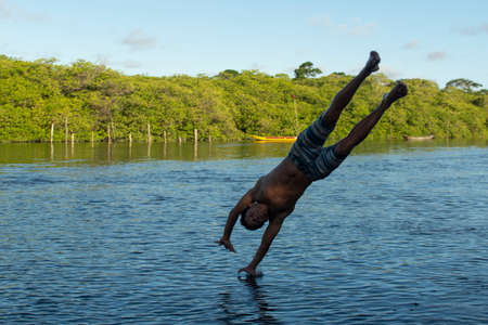 Aratuipe, Bahia, Brazil - February 22, 2019: Young people jumping into the Jaguaripe river in...