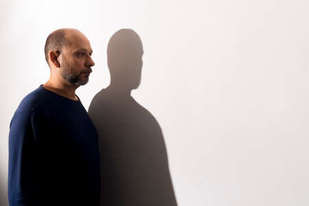 Portrait of a man and his shadow against white wall background. Salvador, Bahia, Brazilの写真素材