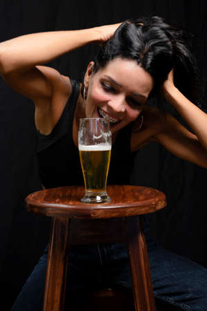 Portrait of a woman with glass of beer against black background. Salvador, Bahia, Brazil.の写真素材