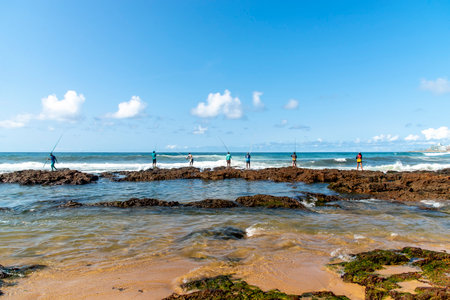 Salvador, Bahia, Brazil - October 10, 2021: Fishermen with fishing rod on the rocks fishing on the famous Boca do Rio beach in Salvador, capital of Bahia, Brazilのeditorial素材