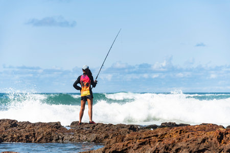 Salvador, Bahia, Brazil - October 10, 2021: Fisherman woman with fishing rod on the rocks fishing on the famous Rio Vermelho beach in Salvador, capital of Bahia, Brazilのeditorial素材