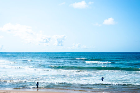 Salvador, Bahia, Brazil - October 10, 2021: Two fishermen with fishing rod on the beach of Boca do Rio in Salvador in the Brazilian state of Bahia.のeditorial素材