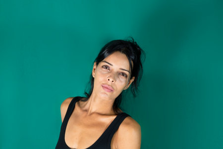Portrait of standing adult model in black dress against dark green background. Salvador, Bahia, Brazil.の写真素材