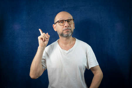 Portrait of a bearded man wearing eyeglasses against a blue background. Salvador, Bahia, Brazil.