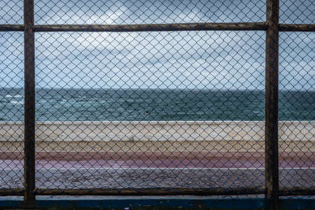Sports fence seen during the rain against the ocean. Salvador, Bahia, Brazil.の写真素材
