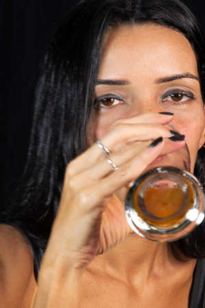 Portrait of a woman with glass of beer against black background. Salvador, Bahia, Brazil.の写真素材