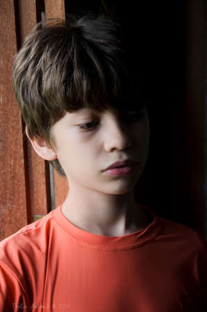 Portrait of a boy at the window wearing orange shirt. Salvador, Bahia, Brazil.の写真素材