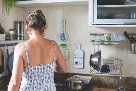 Young woman from the back making food in the kitchen.の写真素材
