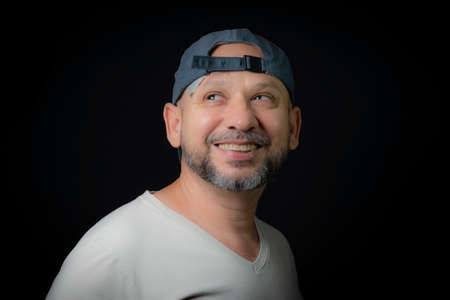 Portrait of a bald bearded man wearing cap looking at camera against black background. Salvador, Bahia, Brazil.の写真素材