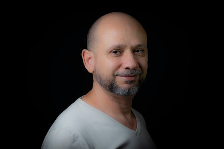 Portrait of a bald bearded man looking at the camera against a black background. Salvador, Bahia, Brazil.の写真素材