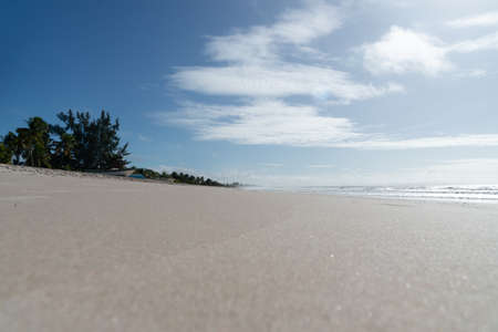 Clear and dense sand against blue sky with clouds and strong sun on Guaibim beach in Valenca city in Bahia, Brazil.の写真素材