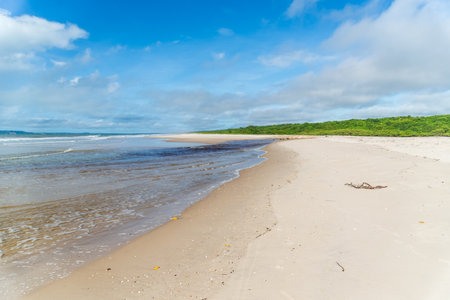 Clear and dense sand against blue sky with clouds and strong sun on Guaibim beach in Valenca city in Bahia, Brazil.の写真素材