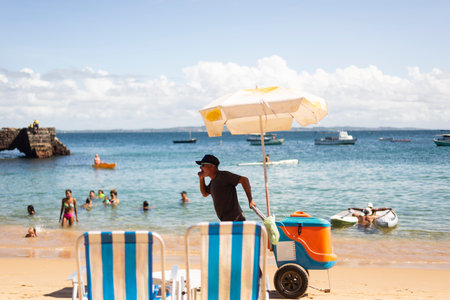 Salvador, Bahia, Brazil - June 04, 2022: Street vendors walk on the sand of Porto da Barra beach in Salvador, Bahia.のeditorial素材