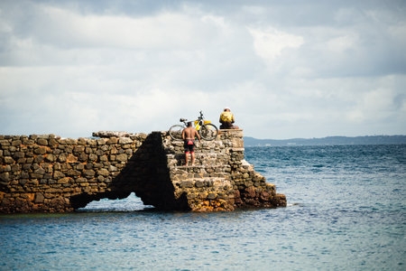 Salvador, Bahia, Brazil - June 04, 2022: People walk on top of the stone breakwater of Porto da Barra beach in Salvador, Bahia.のeditorial素材