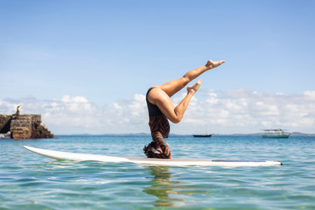 Salvador, Bahia, Brazil - June 04, 2022: Woman stands upside down on a surfboard at Porto da Barra beach in Salvador, Bahia.のeditorial素材