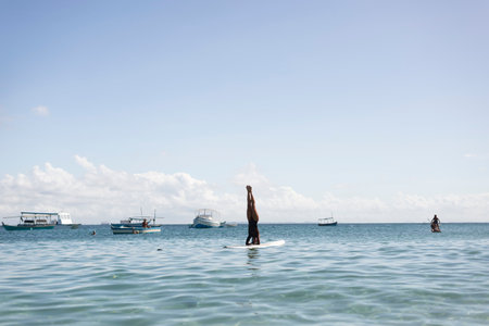 Salvador, Bahia, Brazil - June 04, 2022: Woman stands upside down on a surfboard at Porto da Barra beach in Salvador, Bahia.のeditorial素材