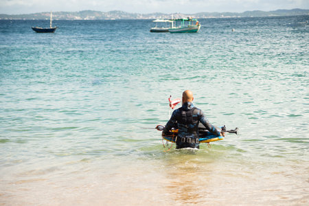 Salvador, Bahia, Brazil - June 04, 2022: Man entering the sea with diving equipment. Porto da Barra beach, in Salvador, state of Bahia, Brazil.のeditorial素材
