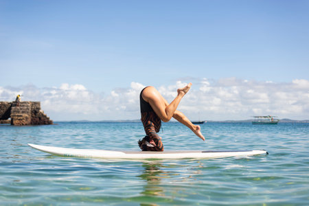 Salvador, Bahia, Brazil - June 04, 2022: Woman stands upside down on a surfboard at Porto da Barra beach in Salvador, Bahia.のeditorial素材