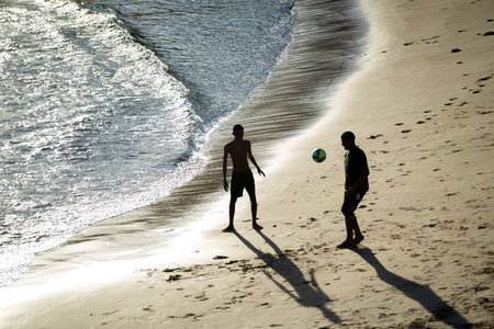 Salvador, Bahia, Brazil - November 01, 2021: Two young men playing beach soccer at Rio Vermelho beach in Salvador, Bahia in the late afternoon.のeditorial素材