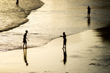 Salvador, Bahia, Brazil - November 01, 2021: People walking on the sand of Rio Vermelho beach in Salvador, Bahia, in the late afternoon.のeditorial素材