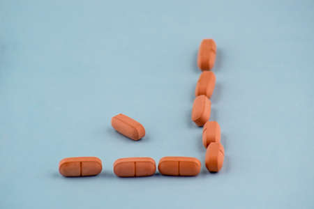 Simple pile of brown pills. Medicines, pills stacked on blue background. Medical supplies.の写真素材