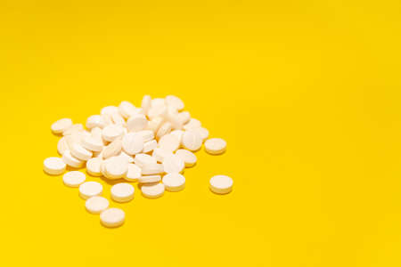 Several white colored pills laid out on top of a blue surface. Medical supplies.の写真素材