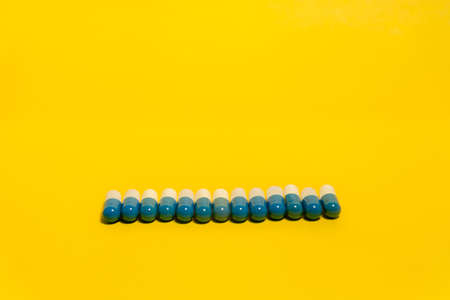 Blue and white colored pills in a row on a blue surface. Medical supplies.の写真素材