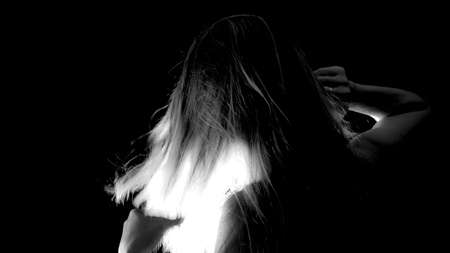 Portrait of a Shirtless Woman Back to the Camera Against Black Background. artistic nude.の写真素材