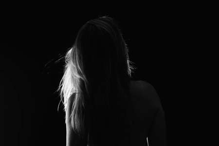 Portrait of a Shirtless Woman Back to the Camera Against Black Background. artistic nude.の写真素材