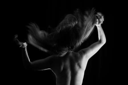 Portrait of a Shirtless Woman Back to the Camera Against Black Background. artistic nude.の写真素材