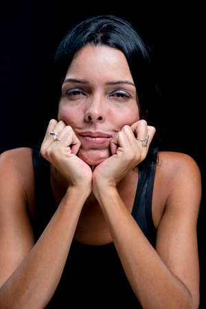 Studio portrait of young woman looking at camera against simple studio black background. She wears a black t-shirt.の写真素材
