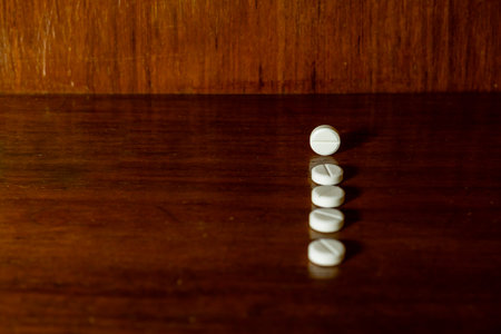 Simple pile of white pills, medicines, pills stacked on brown background. Medical supplies.の写真素材
