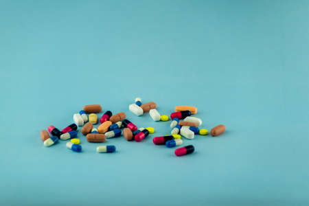 Simple pile of colorful pills. Medicines, pills stacked on blue background. Medical supplies.