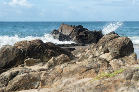 A wave breaks about a rock during a curtain on the sea. Barra beach lighthouse, Salvador, Brazil.の写真素材