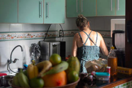 Caucasian woman with her back to her cooking in the kitchen. Salvador, Bahia, Brazil.の写真素材