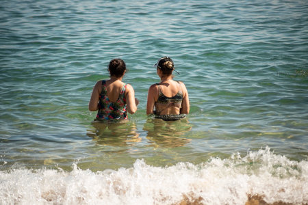 Mother and daughter in bikini entering the water at Porto da Barra beach in Salvador, Bahia.の写真素材