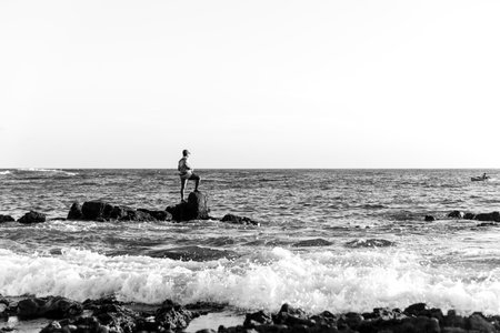 Salvador, Bahia, Brazil - December 11, 2021: Fisherman fishing from above the slippery rocks of Rio Vermelho beach in Salvador, Bahia.のeditorial素材