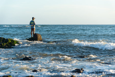 Salvador, Bahia, Brazil - December 11, 2021: Fisherman fishing from above the slippery rocks of Rio Vermelho beach in Salvador, Bahia.のeditorial素材