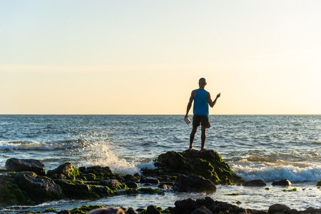 Salvador, Bahia, Brazil - December 11, 2021: Fisherman fishing from above the slippery rocks of Rio Vermelho beach in Salvador, Bahia.のeditorial素材